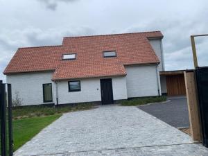 a white house with a red roof and a driveway at Villa Houtave in Zuienkerke