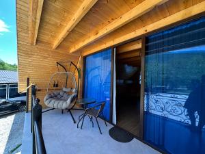 a porch with a swing and a chair on a house at RIVERSIDE Cottage in Martvili