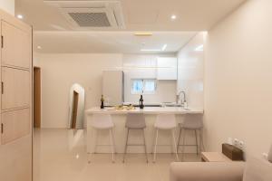 Eine Küche mit weißen Schränken und einer Theke mit Hockern in der Unterkunft MH Hotel 2 in Jeonju