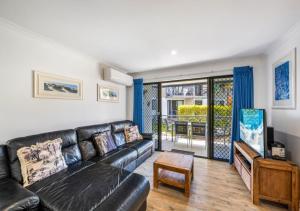 a living room with a black leather couch at Ivory Palms Resort Noosa in Noosaville