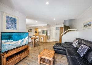 a living room with a black couch and a flat screen tv at Ivory Palms Resort Noosa in Noosaville