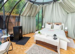 a bedroom with a bed and a tv in a tent at Entre Ciel et Rivière in Bouillon