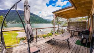 a deck with a desk and an umbrella and a lake at Seecamping & Pension Mentl in Landskron