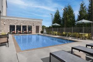 a swimming pool with tables and chairs next to a building at Hampton Inn Kernersville in Kernersville