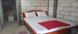 a bedroom with a bed with a red blanket on it at Komachi House in Limbung