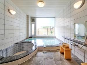 a large bathroom with a tub and a window at Shirahama Onsen Kisyu Hanto in Shirahama