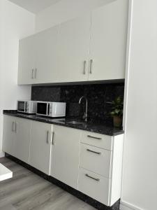 a kitchen with white cabinets and a sink at Albergue Adventus in Padrón +8 photos