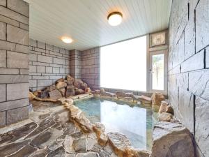 a large swimming pool in a room with a stone wall at Shirahama Onsen Kisyu Hanto in Shirahama