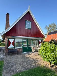a red barn with two chairs in front of it at Vakantiewoning Uutbloazen in Lievelde