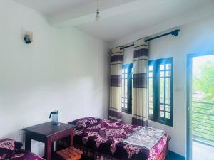 a bedroom with a bed and a table and windows at K K Kumar Guest in Norwood