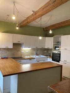 a kitchen with white cabinets and a wooden counter top at Charmant duplex 8 couchages 75 m2, terrasse 12 m2 dans village typique héraultais in Tourbes