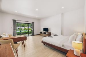 a bedroom with a bed and a desk and a television at Anahata Resort in Lipa Noi
