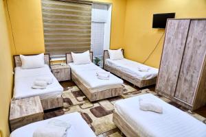 three beds in a room with yellow walls at Dilbar Guest House in Samarkand