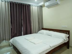 a bedroom with a bed with white sheets and a window at Hotel Brinda in Kākināda