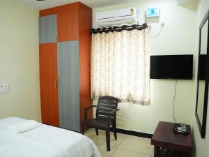 a bedroom with a bed and a chair and a window at Hotel Brinda in Kākināda