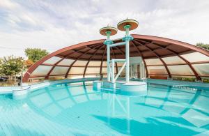 a large swimming pool with a large curved building at Aquasol Resort in Mosonmagyaróvár