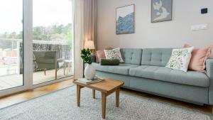 a living room with a blue couch and a table at Baltic Pine by Pino Resort in Gdańsk