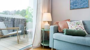 a living room with a blue couch and a balcony at Baltic Pine by Pino Resort in Gdańsk