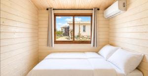 a bed in a small room with a window at The Heart Cabin בקתת הלב in Kidmat Tsvi