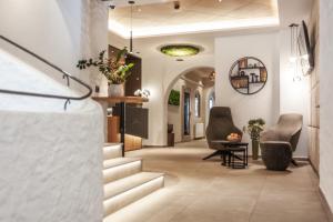 a hallway with stairs and chairs in a house at Hotel Hubertus mit Summercard in Sölden