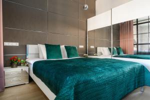 a bedroom with two large beds with green sheets at Lumina I Comfy Loft with Parking I View of the Lake in Łódź