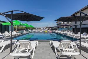 a swimming pool with white chairs and umbrellas at Fenix in Solotvyno