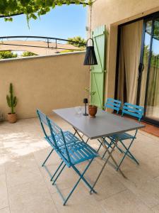 a table and two blue chairs on a patio at L'Oléastre en Luberon in Grambois