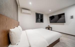 a bedroom with a white bed and a flat screen tv at Hotel Seven Step in Incheon