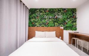 a bedroom with a bed and a green wall at Hotel Seven Step in Incheon