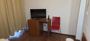 a television sitting on a desk with a red chair at Hotel Timisoara Sannicolau Mare in Sînnicolau Mare