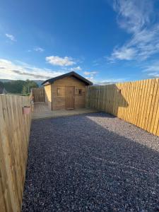 a wooden building with a fence and a gate at Jacobite Cabin in Inverlochy