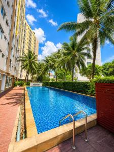 a swimming pool with palm trees and buildings at Modern 12th Floor Condo Walk to Phuket Old Town with Pool & Gym in Phuket