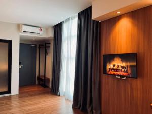 a living room with a tv on a wall at Roxy Hotel Aiman in Kuching