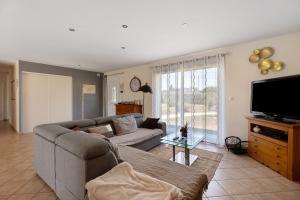 a living room with a couch and a flat screen tv at Le Refuge des deux Cœurs - Beauval in Villefranche-Sur-Cher