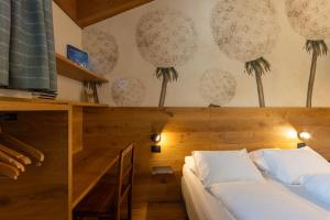 a bedroom with a bed with white sheets and palm trees on the wall at Maison Luboz - Courmayeur in Courmayeur