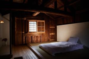 a bedroom with a bed in a room with a window at 蔵宿あさぎやみたけ in Ome