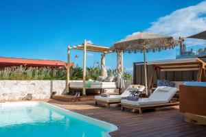 a pool with chairs and an umbrella next to a house at Esperides Resort Crete, The Authentic Experience in Hersonissos