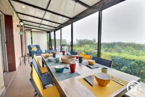 a dining room with a table and chairs and windows at Ar gwelva in Cléguérec