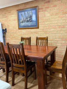 a wooden table with four chairs and a painting of a ship at Corner unit in Geraldton in Geraldton