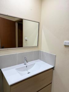 a bathroom with a white sink and a mirror at Corner unit in Geraldton in Geraldton