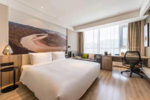 a hotel room with a large bed and a desk at Atour Hotel Shuangyong Ave in Yan'an
