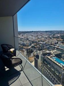 a chair on a balcony with a view of a city at Sky Apartment , 22th Floor Mercury Tower in St. Julianʼs