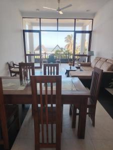 a dining room with a table and chairs and a couch at Ninas Beach Resort in Habaraduwa Central