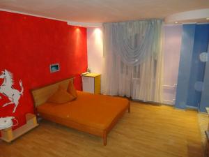 a room with a bed and a red wall at Studio on Sovetskaya 206 in Biysk