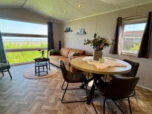 a living room with a table and chairs and a couch at Chalet direct aan Waddenzee in Westerland