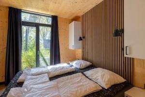 a bedroom with a bed and a large window at Zicht op Twente - Spa lodges in Markelo +61 photos