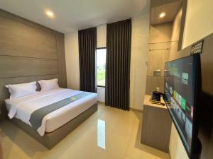 a bedroom with a bed and a flat screen tv at The Quadrant Hotel Ocarina Batam in Batam Center