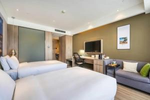 a hotel room with two beds a couch and a tv at Atour Hotel Shuangyong Ave in Yan'an