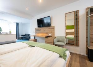 a bedroom with a bed and a flat screen tv at Berghotel Kristall in Idar-Oberstein