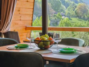 a table with a bowl of fruit and wine glasses at Forest Cuib in Predeluţ